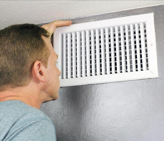 guy looking into an air duct to see how clean and healthy it is.