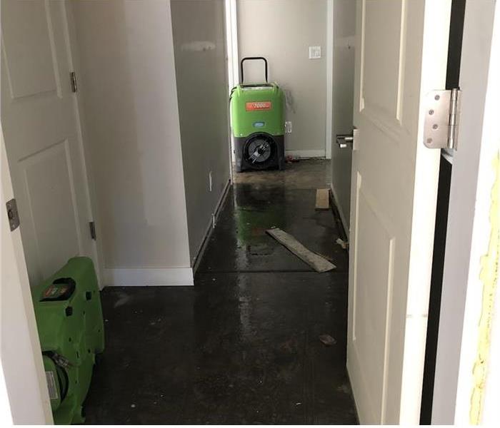 A home with water damage in its hall and several clean up machines