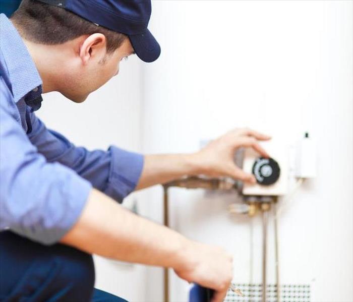 Person inspecting a water heater.